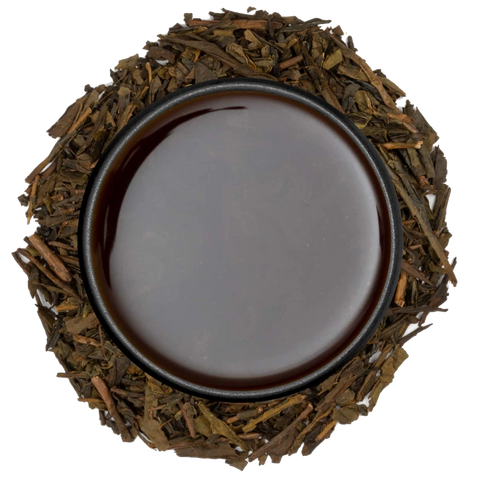A cup of reddish-brown hojicha seen from above, ringed by roasted hojicha leaves on a white background